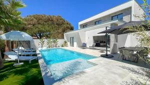 a swimming pool in front of a house at La Maison de La Plage in Le Grau-dʼAgde