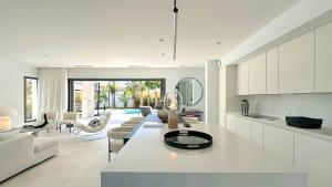 a living room with white furniture and a kitchen at La Maison de La Plage in Le Grau-dʼAgde