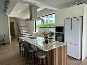 een keuken met een witte koelkast en een aanrecht met krukken bij Brand new 3 bedrooms villa in Ko Samui