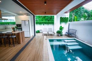 een overdekt zwembad met een bar en een keuken en een huis bij Brand new 3 bedrooms villa in Ko Samui