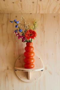 a red vase with flowers on a shelf at Tetris Tiny House in Den Bosch