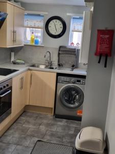 a kitchen with a washing machine and a clock on the wall at 2 Beach House in Bridlington +14 photos