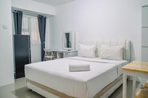 a bedroom with a large white bed and a desk at Minimalist Studio Room at Urbantown Serpong Apartment By Travelio in Tangerang +17 photos