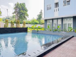 a swimming pool in front of a building at Minimalist Studio Room at Urbantown Serpong Apartment By Travelio in Tangerang