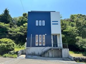 a blue building with a staircase in front of trees at 白浜温泉付き貸別荘b-72 in Shirahama