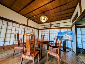 a dining room with a wooden table and chairs at 1棟貸切で家族仲間と焚火バーベキューを楽しめる古民家NanasawaBasshouse in Atsugi