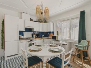 a kitchen with white cabinets and a white table and chairs at Maison pour 4 avec grand jardin - Pont Aven in Pont-Aven +13 photos