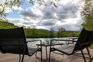 two chairs and a table on a deck next to a lake at simply-una in Bihać