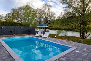 a swimming pool with two chairs and an umbrella at simply-una in Bihać