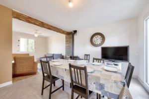 a dining room with a table and chairs and a clock at Maison pour 6 avec terrasse et jardin in Guissény
