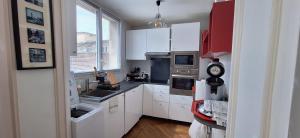 Elle comprend une petite cuisine avec des placards blancs et une fenêtre. dans l'établissement St André Centre Rouen Standing, à Rouen