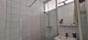 une salle de bain carrelée blanche avec une douche et un lavabo dans l'établissement St André Centre Rouen Standing, à Rouen