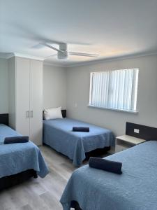 une chambre avec deux lits et un ventilateur de plafond dans l'établissement Experience Lancelin Holiday Park, à Lancelin