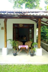 a patio with two chairs and a table with plants at Hiriketiya Don Simon Villa in Dickwella