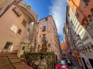 a narrow street in a city with buildings and a car at lovingenoa Light - Passion in Genoa