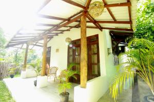 a house with a covered porch with plants at Hiriketiya Don Simon Villa in Dickwella