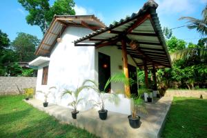 a small white house with potted plants in front of it at Hiriketiya Don Simon Villa in Dickwella