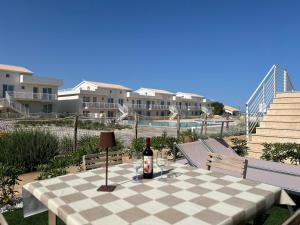 a table with a bottle of wine sitting on a checkered table cloth at Le Voyage Holiday Home Marzamemi in Marzamemi