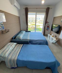 two beds in a bedroom with a large window at Le Voyage Holiday Home Marzamemi in Marzamemi +27 photos