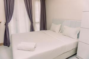 a bed with white sheets and pillows in a bedroom at Nice and Comfort Studio Apartment at Tokyo Riverside PIK 2 By Travelio in Rawalembang
