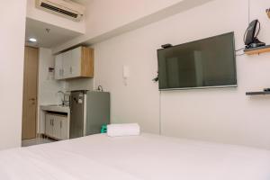 a kitchen with a refrigerator and a television on the wall at Nice and Comfort Studio Apartment at Tokyo Riverside PIK 2 By Travelio in Rawalembang
