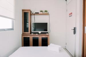 une chambre avec une télévision sur un meuble en bois dans l'établissement Homey and Comfort Stay 2BR Pakubuwono Terrace Apartment By Travelio, à Jakarta