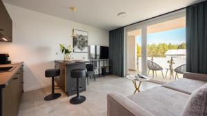 sala de estar con sofá y cocina con balcón en Flatbook Apartamenty - Sztutowo Baltic Garden z Basenem i Parkingiem, en Sztutowo
