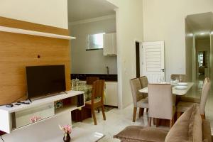 a living room with a television and a dining room at Paracuru casa temporada Villa Ariane in Paracuru