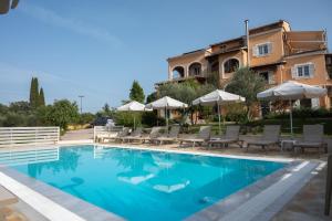 a swimming pool with chairs and umbrellas next to a building at Pasiphae Holiday Apartments in Kontokali