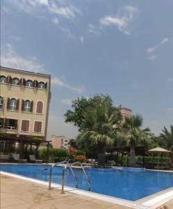 a pool at a resort with palm trees and a building at The Gardens home in Dubai