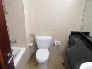 a bathroom with a white toilet and a bath tub at The Gardens home in Dubai