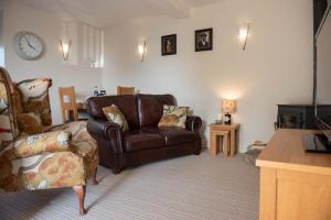 a living room with a leather couch and a chair at Ash Cottage, Castle Carrock, Nr Carlisle in Castle Carrock