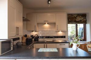 a kitchen with white cabinets and a black counter top at Ash Cottage, Castle Carrock, Nr Carlisle in Castle Carrock +2 photos