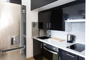 a kitchen with black cabinets and a stainless steel refrigerator at Studio Premium au Calme avec Terrasse Vue Mer et Parking in Nice