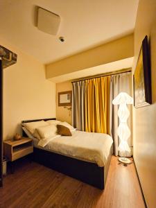 a bedroom with a bed and a lamp and a window at Galini Suites in Manila +24 photos