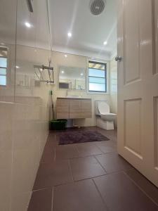 a bathroom with a shower and a toilet and a door at Comfortable Queen Room in Spacious House with Backyard - GA3 in Chullora