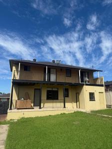 a large yellow house with a balcony on top at Comfortable Queen Room in Spacious House with Backyard - GA3 in Chullora +11 photos
