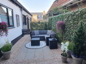 a patio with a couch and some plants and flowers at Bij ons op de Hoep. in Schagen