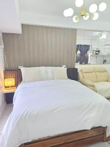 a bedroom with a large white bed and a couch at Steff's Condo 722 at Centrio Tower in Cagayan de Oro