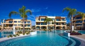 un complejo con piscina con palmeras y edificios en Brand New Stunning Apartment with Pool Views, Dionysus Village, Aphrodite Hills, en Kouklia