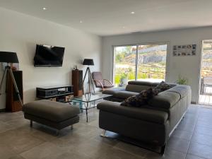 a living room with two couches and a tv at Paisible villa avec piscine proche du Pic Saint-Loup in Saint-Jean-de-Cuculles