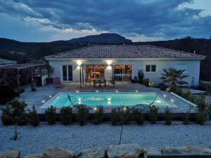 a villa with a swimming pool in front of a house at Paisible villa avec piscine proche du Pic Saint-Loup in Saint-Jean-de-Cuculles