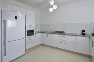 Ariston First Line Lake View في طبرية: مطبخ أبيض مع أجهزة بيضاء ودواليب بيضاء