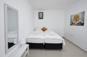 Ariston First Line Lake View في طبرية: غرفة نوم بيضاء بسريرين ومرآة