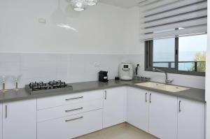 Ariston First Line Lake View في طبرية: مطبخ بخزائن بيضاء ومغسلة ونافذة +15 صورة