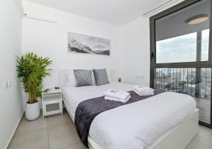 a bedroom with a white bed and a large window at My View 2 bedroom apartment by the lake in Tiberias