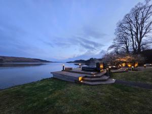 ein Dock am Ufer eines Sees bei Nacht in der Unterkunft Fyne Edge - A Luxurious Lochside Haven in Minard