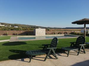 two lawn chairs and an umbrella next to a pool at Finca Laxuan in Cádiz
