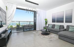 a living room with a couch and a view of the ocean at Michelangelo Kinneret Family Apartment in Tiberias