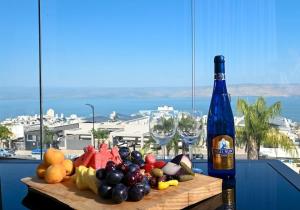 a bottle of wine and a plate of fruit on a table at Michelangelo Kinneret Family Apartment in Tiberias
